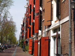 A row of narrow brick canal houses with stepped gables, reflected in the water