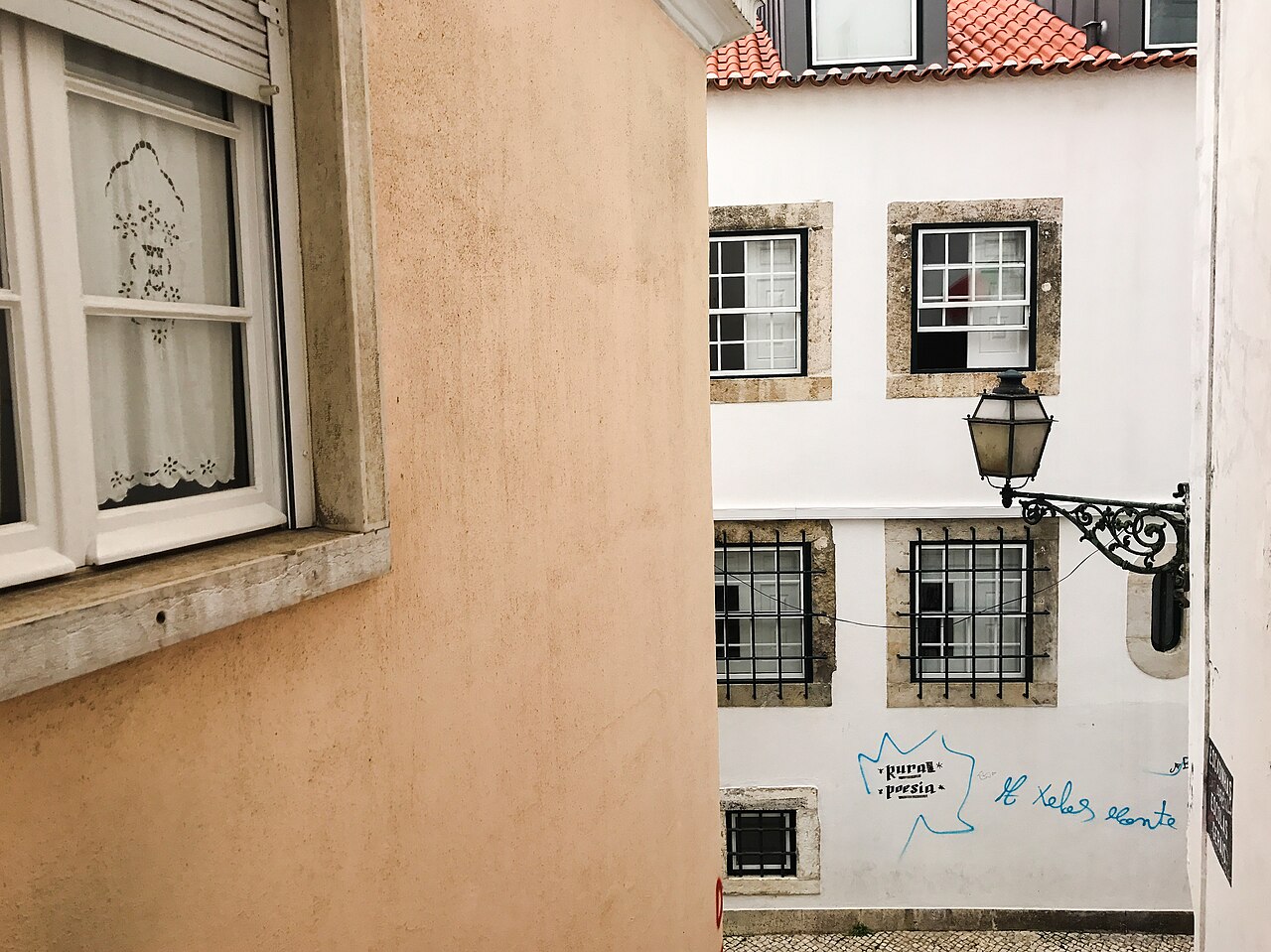 A steep narrow street in Alfama with washing hung between tiled buildings and steps climbing away