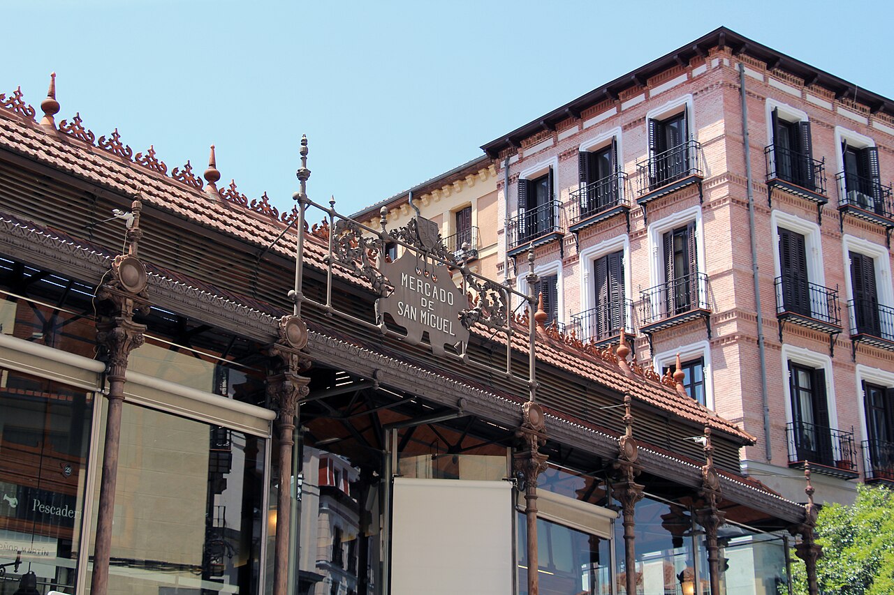 Glass and iron facade of the Mercado de San Miguel with people at the counters inside