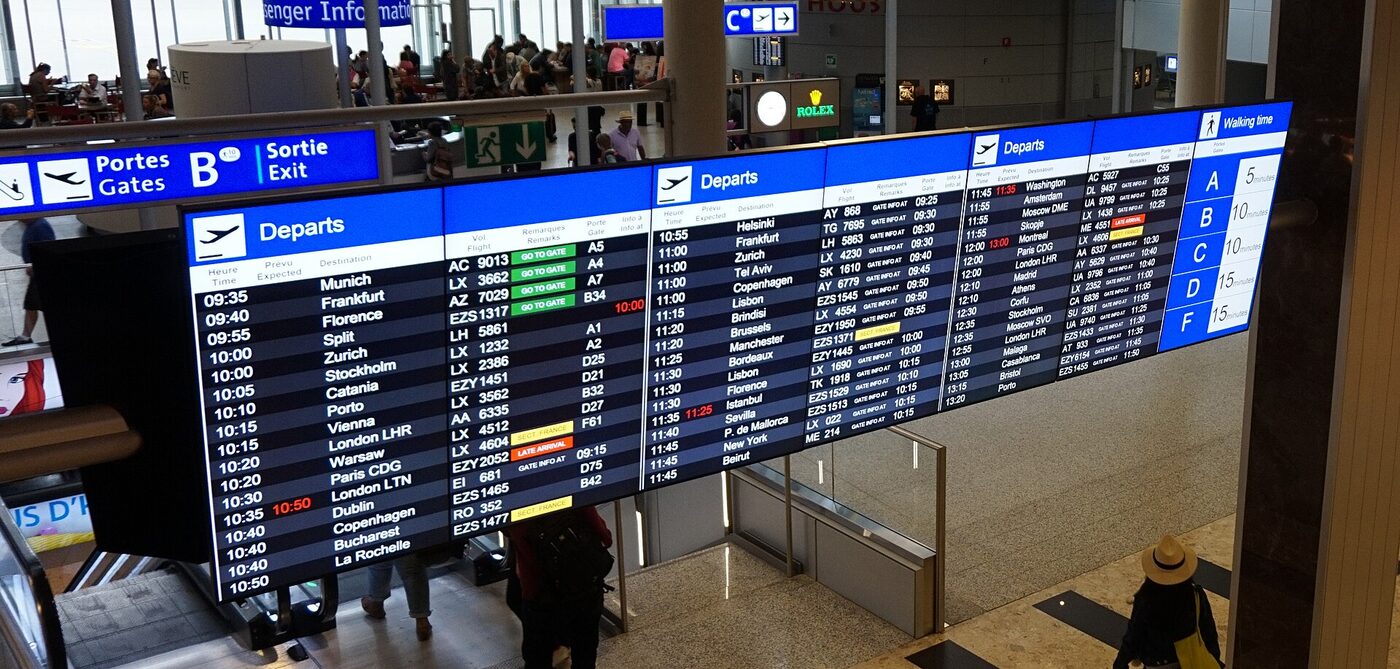 A departure board in an airport terminal listing flights and gate numbers