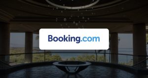 Booking.com logo over a hotel lobby with an ocean view