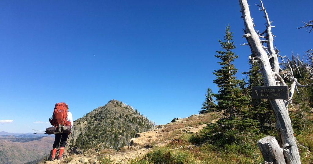 Backpacker on a mountain ridge trail looking towards a rocky summit
