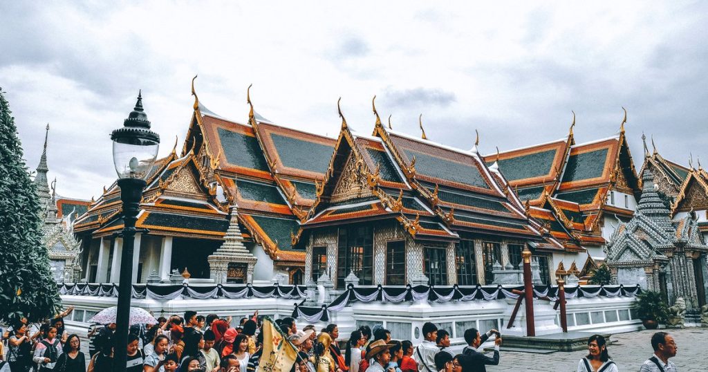 Grand Palace complex in Bangkok with crowds of visitors under a bright sky