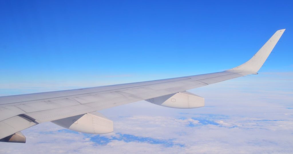 Aircraft wing seen from a cabin window above a layer of clouds
