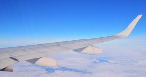 Aircraft wing seen from a cabin window above a layer of clouds