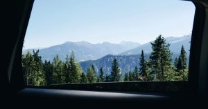 View from a car window of green mountains and pine forest