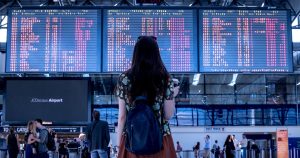 Woman with a backpack standing in front of airport departure boards